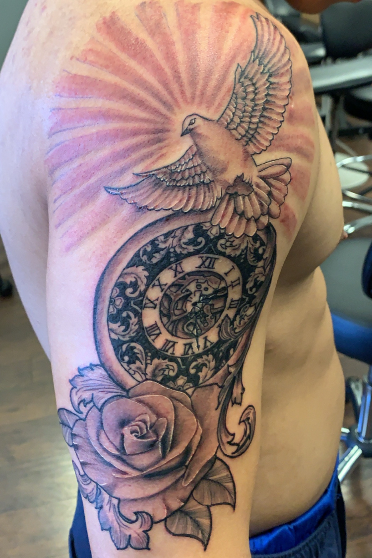 Tattoo đồng hồ ở bắp tay cùng hoạ tiết bồ câu và hoa hồng